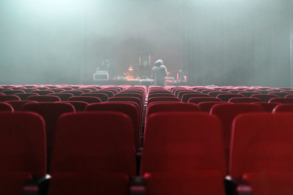people sitting on red chairs watching a band performing on stage