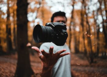black DSLR camera floating over man's hand at the woods